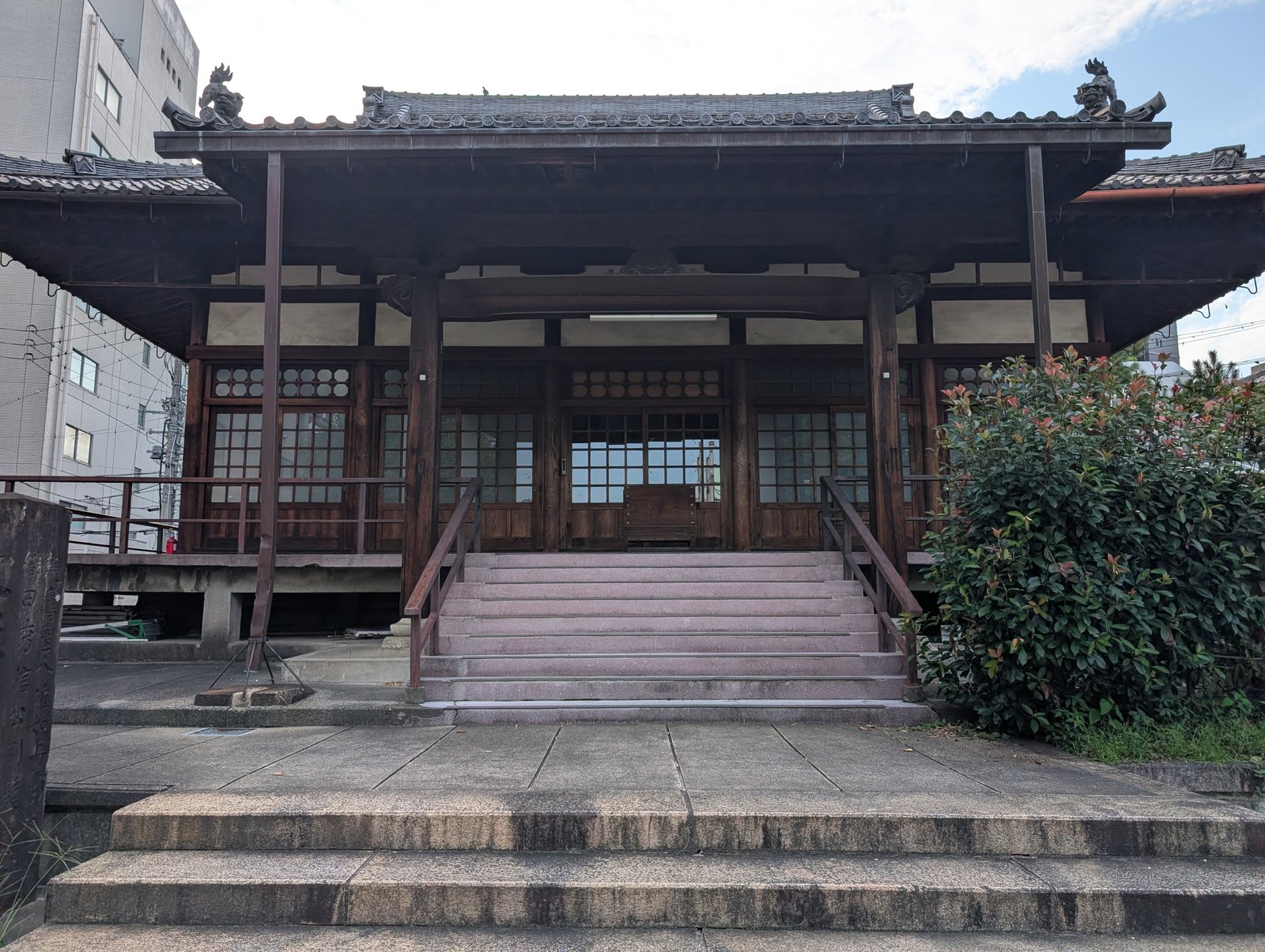 円徳寺の本堂。左右にビルが迫り、電線が横切る