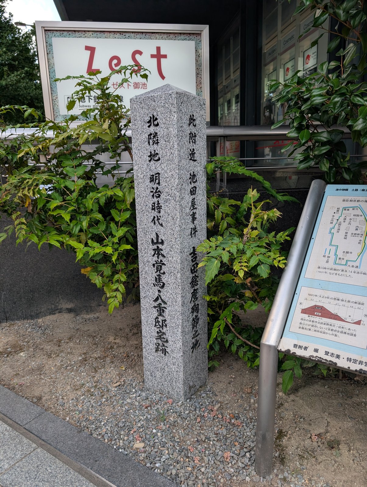 薬局の隣に立つ石標。「此附近 池田屋事件 吉田稔麿殉節之地」と「北隣地 明治時代 山本覚馬・八重邸宅跡」が一本に刻まれている