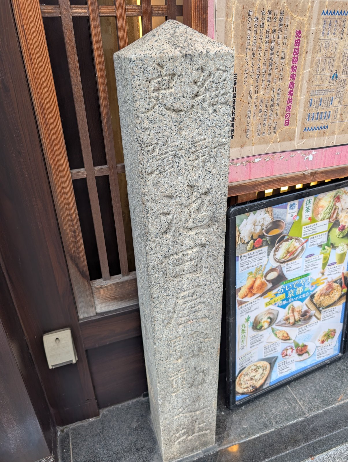 店先に立つ「史蹟 池田屋騒動之址」の石碑。右上の貼り紙が「池田屋騒動殉難者供養の日」の案内で、その下は店のメニュー