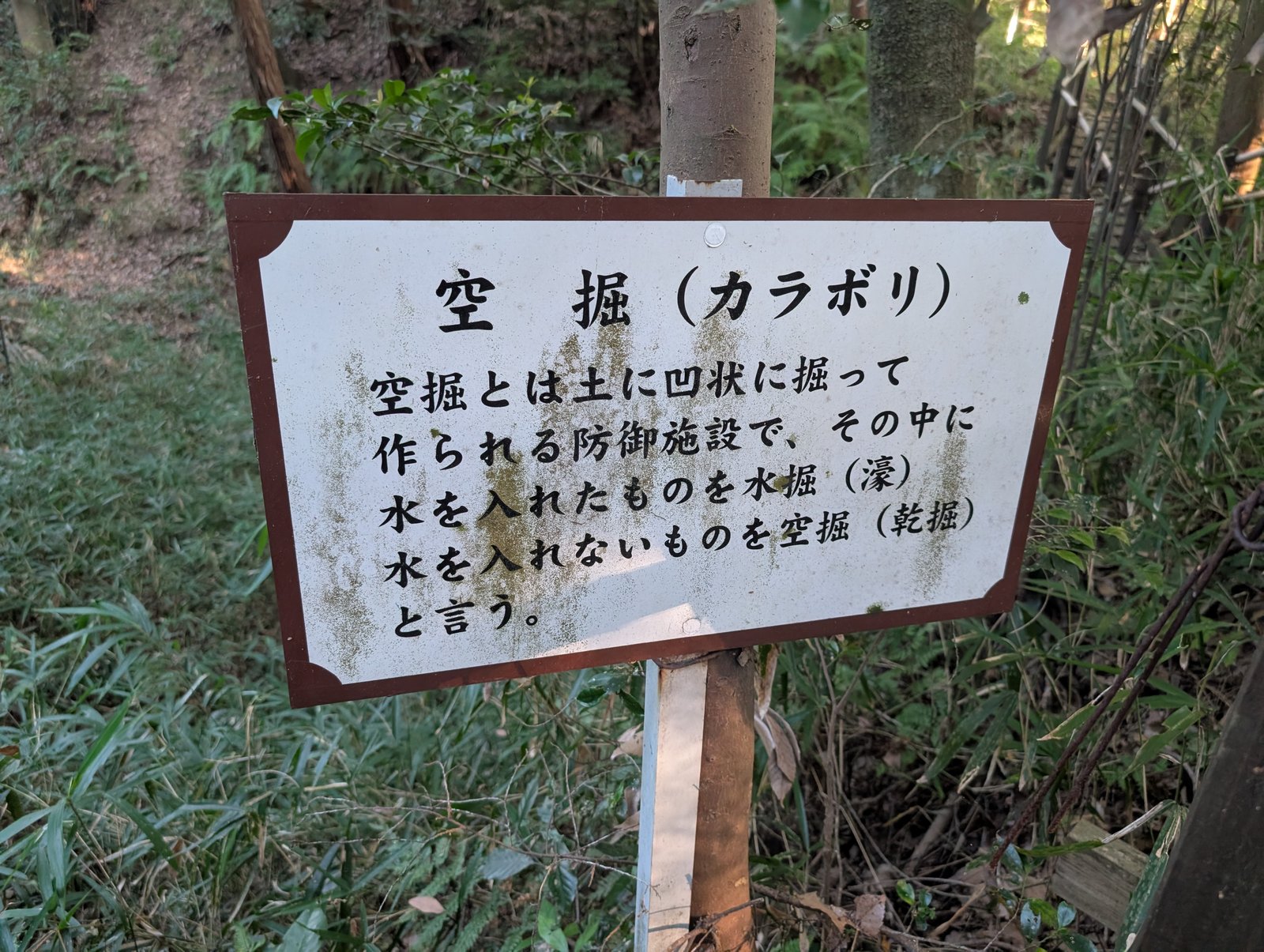 「空堀（カラボリ）」の標識。土に凹状に掘った防御施設と説明がある