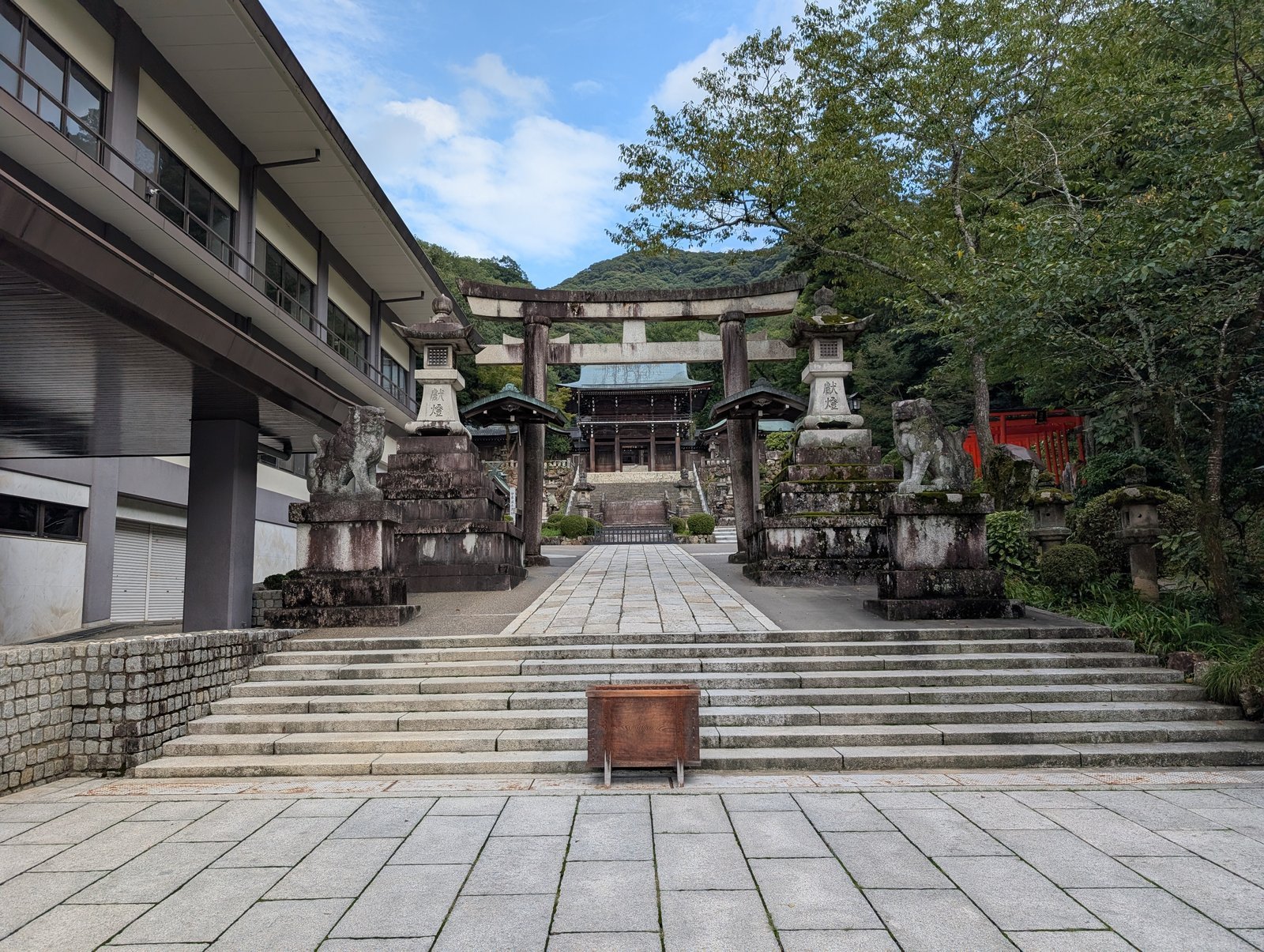 石鳥居の奥に神門と拝殿、その先に金華山（2026年9月撮影）